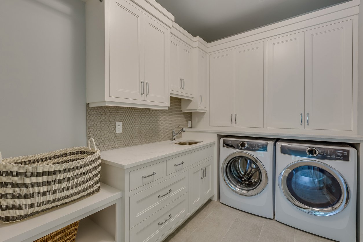 spotless laundry room with white cabinets and appliances