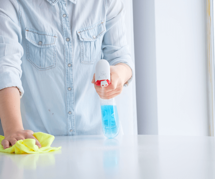 A woman cleaning a table with a spray bottle, ensuring a spotless surface at Thornton