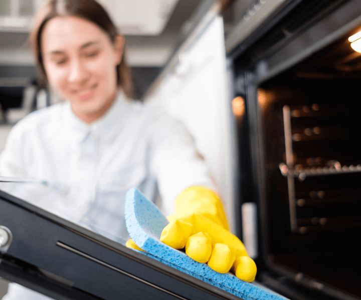 A woman performing a deep clean of an oven, showcasing the expert services of Chloe's Cleaning Company in Denver