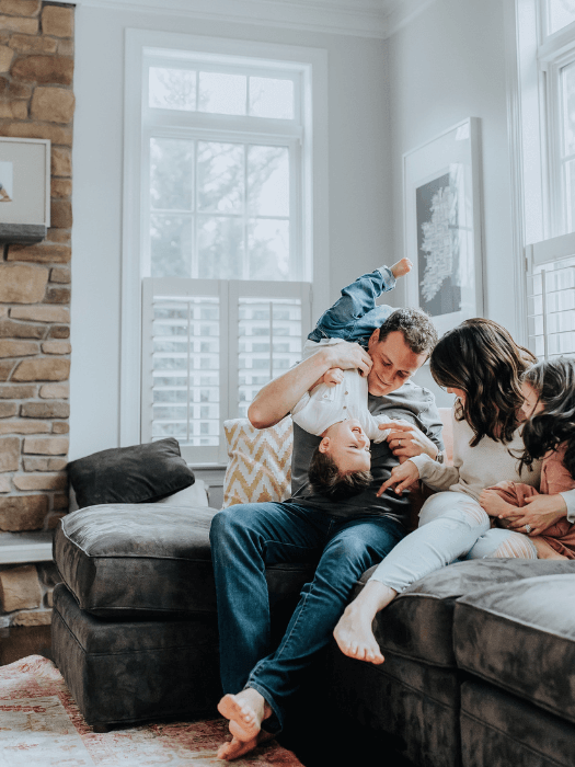 Family enjoying play time on a couch in a clean living room, showcasing professional Denver cleaning services